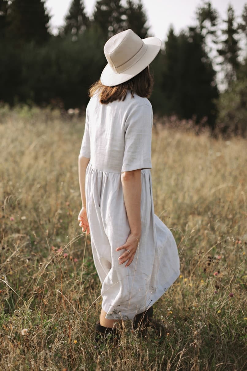 Girl walking through meadow in linen dress
